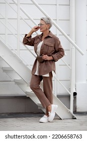 Fashionable woman stands. Short hair Model wears beige business suit with pants and jacket, belt purse, fashion accessories, loafers. Trend multilayered outfit. Fashion, style clothes - Shutterstock ID 2206658763