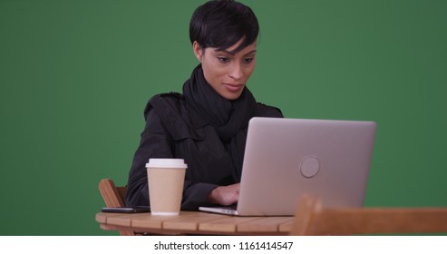 Fashionable Woman Using Laptop Computer At A Cafe Table On Green Screen