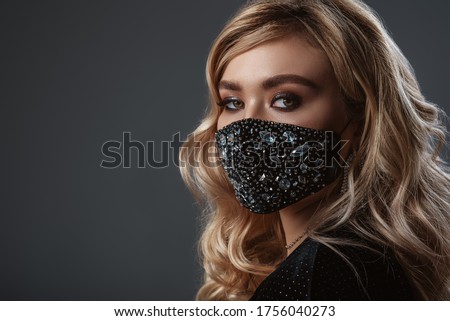 Fashionable woman wearing trendy  luxury face safety black mask with rhinestones. Stylish outfit during quarantine of coronavirus outbreak.  Close up portrait. Copy, empty space