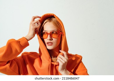 Fashionable woman wearing trendy orange sunglasses, stylish hoodie looking aside. Copy, empty space for text - Shutterstock ID 2118486047