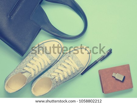 Fashionable women's accessories and devices on a gray background: usb flash drive, bag, wallet, sneakers, pen. Top view. Flat lay.