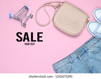 Fashionable women's clothing, shoes and accessories on a pink background.Sale. Bag, jeans, bags, miniature shopping carts. Shopping concept, shopaholic. Copy space. - Powered by Shutterstock