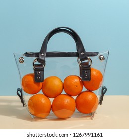 Fashionable women's transparent bag filled with oranges. Creative minimalistic concept.