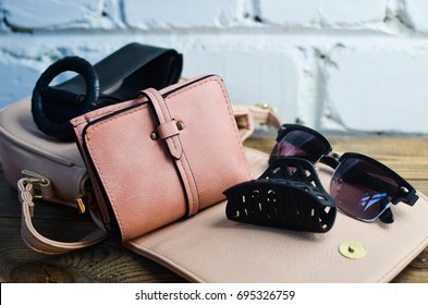 Fashionable women's wallet, leather bag and other accessories on a white brick wall background. Fashionable look.