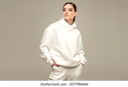 Fashionable young beautiful  woman . Slim girl in an active pose in a white hoodie. Fashion, clothing and style. - Powered by Shutterstock