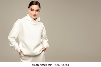 Fashionable young beautiful  woman . Slim girl in an active pose in a white hoodie. Fashion, clothing and style.