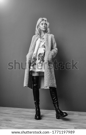 Fashionable young blonde model looking away. Beautiful and fashion young woman posing at grey background.