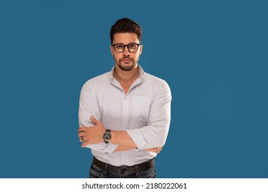 Fashionable young businessman posing on the blue studio background. Copy space. Bearded man wearing eyeglasses looking at the camera.  - Shutterstock ID 2180222061