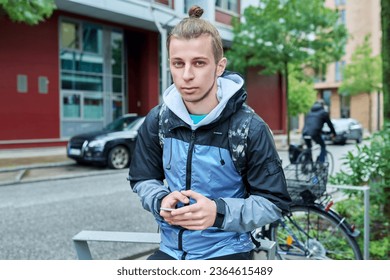 Fashionable young male with backpack using smartphone outdoors in city - Shutterstock ID 2364615489