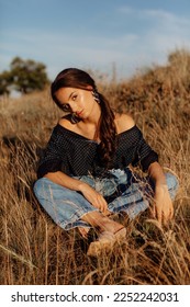 Fashionable young model in boho style clothes on a background of dry grass, field. Female beauty and style concept. Advertisement or clothes sale design. - Shutterstock ID 2252242031
