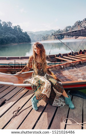 fashionable young model in boho style dress lying on boat 