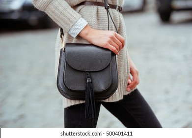 Fashionable Young Woman In Black Jeans, Beige Cardigan And Black Handbag . Street Style .