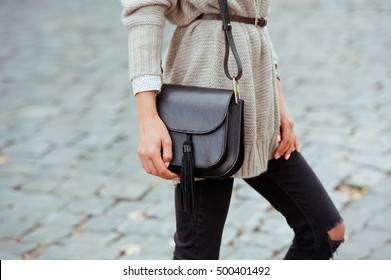 Fashionable Young Woman In Black Jeans, Beige Cardigan And Black Handbag . Street Style .