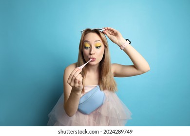 Fashionable Young Woman With Bright Makeup Chewing Bubblegum On Light Blue Background