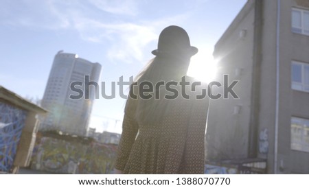 Fashionable young woman model in hat posing on camera. Action. Outdoor portrait of young beautiful fashionable woman with long hair posing. Model looking at camera. Female fashion