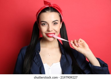 Fashionable Young Woman In Pin Up Outfit Chewing Bubblegum On Red Background