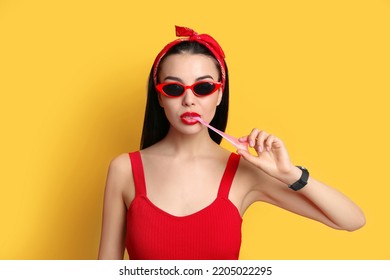 Fashionable Young Woman In Pin Up Outfit Chewing Bubblegum On Yellow Background