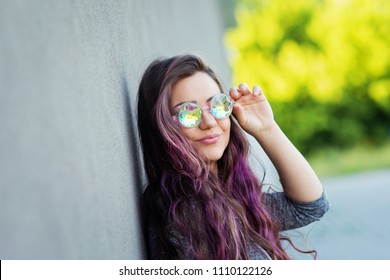 Fashionable young woman with pink long hair wearing iridescent kaleidoscope glasses. Natural lighting, no retouch, closeup, fashion concept, outdoors. - Powered by Shutterstock