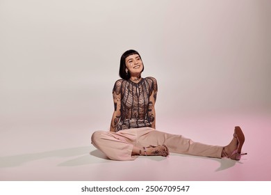 A fashionable young woman showcases her tattoos while sitting playfully.