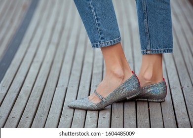 Fashionable Young Woman In Silver Shine Flat Shoes And Blue Jeans On The City Street. Street Style.