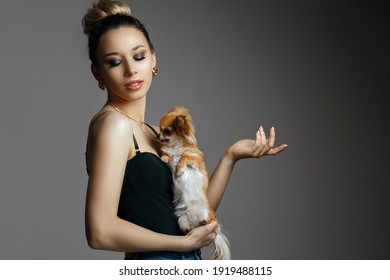 Fashionable Young Woman Wears Stylish Bodysuit Posing With Little Dog At Studio. Space For Text