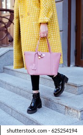 Fashionable Young Woman In Yellow Coat With Rose Handbag In Hand . Street Style .