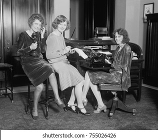 Fashionable young women in a Washington, D.C. office, May 1, 1929. One holds a telephone, another a stenographic pad, and the third sits at a typewriter.