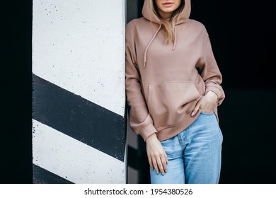 Fasion blonde woman in brown oversize hoodie, glasses and blue jeans, mockup for logo or branding design