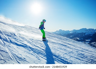 Foto de acción rápida del niño snowboard ir cuesta abajo en snowboard en la vista de la pista alpina de esquí desde el lateral