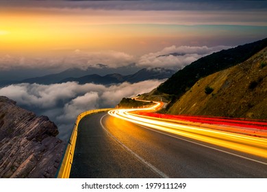 Fast car headlights on European highways. Cargo transportation theme on the highway at sunset. View of traffic and highway running through the mountains. car lights on the highway in the mountain.