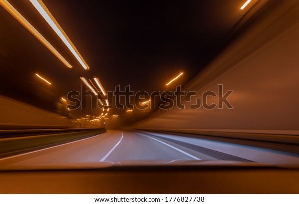 Fast drive through a tunnel with the view through\
the front window of a car.