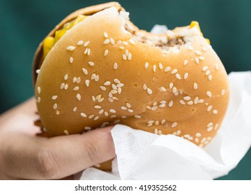 A fast food cheeseburger with a bite taken out of it /  one bite taken out of it / Bitten hamburger.