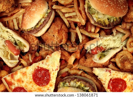 Fast food concept with greasy fried restaurant take out as onion rings burger and hot dogs with fried chicken french fries and pizza as a symbol of diet temptation resulting in unhealthy nutrition.