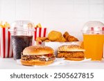 Fast food delivery menu background with various burgers, cheeseburger, nuggets, french fries, fizzy soda drinks. Junk unhealthy fast food, Ultra processed food with low nutrition, high calories value