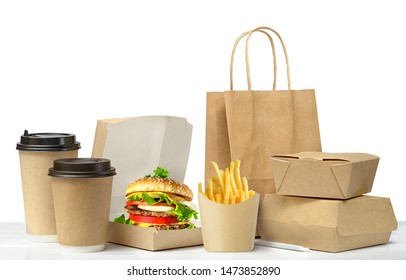 Fast food eco packaging with big lunch set of tasty hamburger, french fries, paper coffee cups, brown paper bag and box on the table isolated on white background