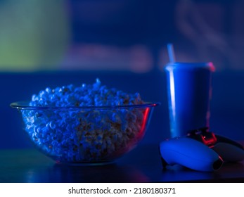 Fast Food - A Large Glass Bowl Of Popcorn, A Soda Drink In A Plastic Cup And A Gamepad. Neon Lighting. Video Games, Recreation, Relaxation, Hobby.