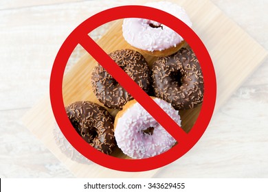 Fast Food, Low Carb Diet, Fattening And Unhealthy Eating Concept - Close Up Of Glazed Donuts On Wooden Board Behind No Symbol Or Circle-backslash Prohibition Sign