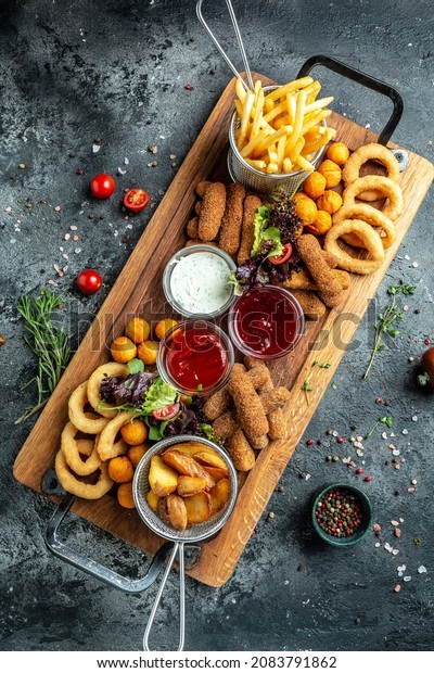 fast food meals mozzarella sticks, onion rings,\
french fries, chicken nuggets and sauce. pub appetizers on a wooden\
board. banner, menu