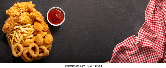 Fast Food Meals : Onion Rings, French Fries, Chicken Nuggets And Fried Chicken On Dark Table, Top View