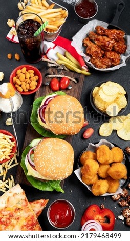 Fast food and unhealthy eating concept - close up of fast food snacks and cola drink on a dark background, top view.