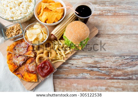 fast food and unhealthy eating concept - close up of fast food snacks and cola drink on wooden table