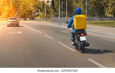 Fast and free food delivery carrying yellow box on a scooter during the day in the city - Shutterstock ID 2299607369