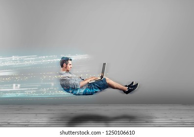 Fast levitating man in a white room using a laptop. High speed browsing. - Shutterstock ID 1250106610