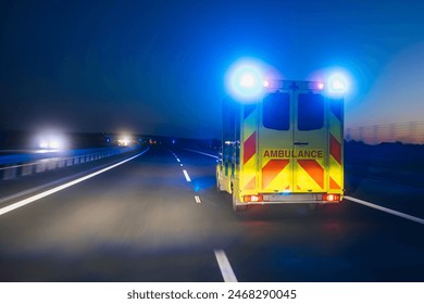 Fast moving ambulance car of emergency medical service on highway at night. Themes healthcare, rescue and urgency.
