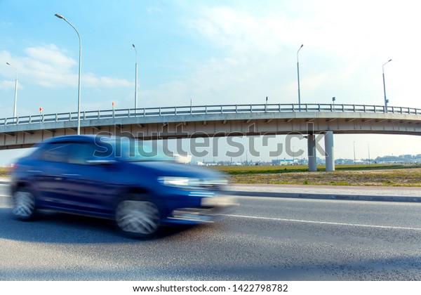 fast moving blurred blue car on the background of
a trestle bridge