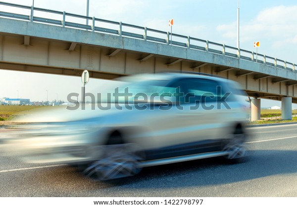 fast moving blurred white car on the background of\
a trestle bridge