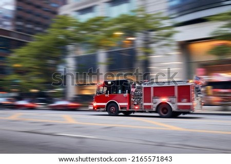 Fast moving fire engine on city street. Firefighters in blurred motion. Themes rescue, urgency and help.
