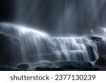 Fast moving waterfall cascade flowing down wet rocks