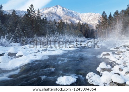 Fast non-freezing mountain river near the village of Arshan on a frosty January day against the background of the snow-capped mountains of the Eastern Sayans