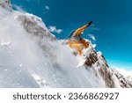 Fast professional snowboarder jumps at offpiste ski slope in cloud of powder snow